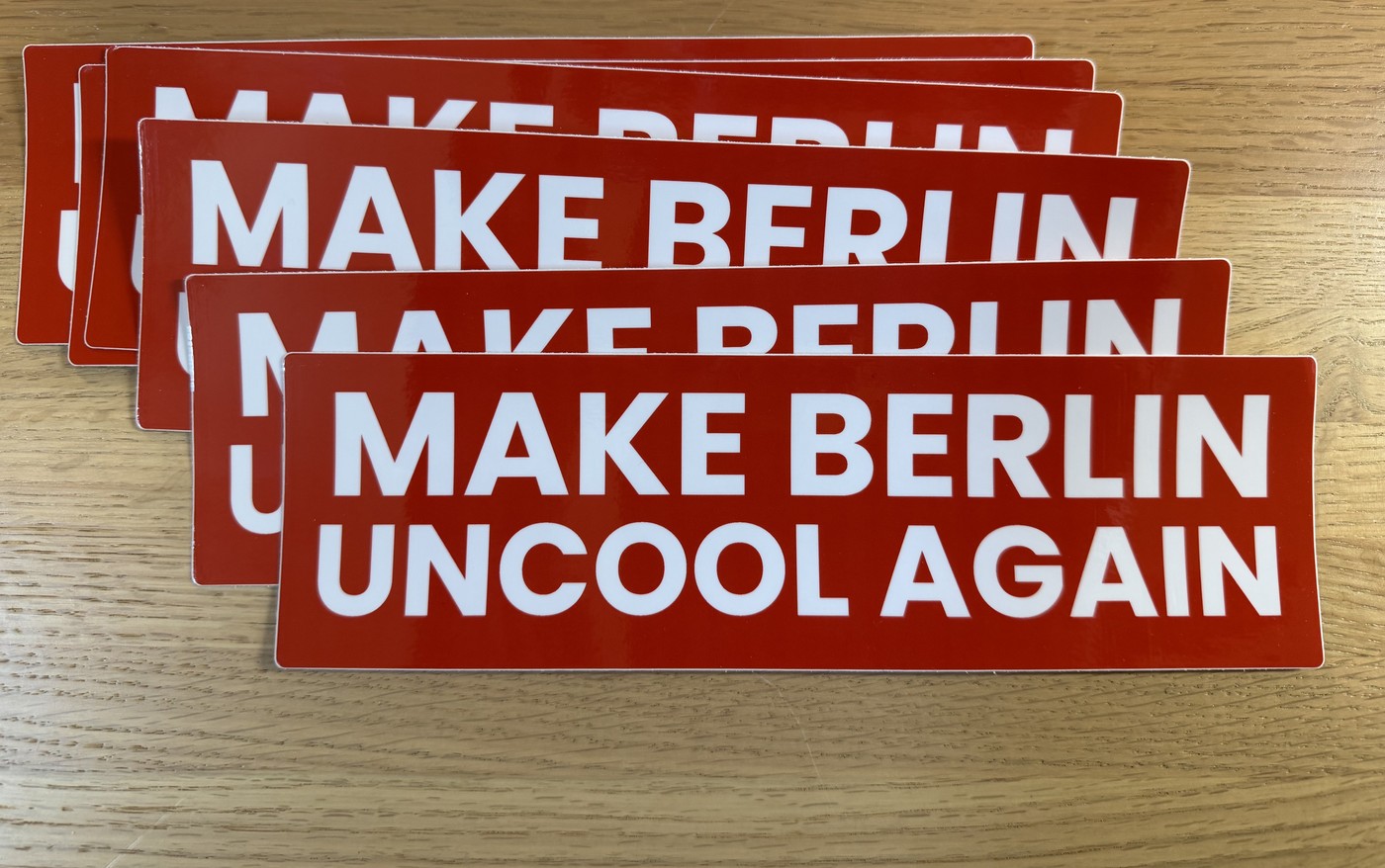 Stack of red bumper stickers reading Make Berlin Uncool Again