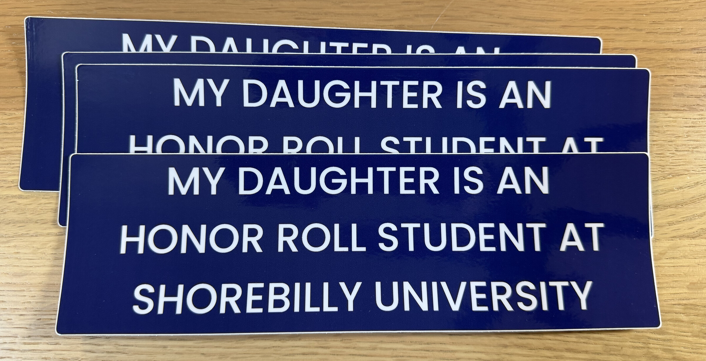 White bumper sticker reading My daughter is an honor roll student at Shorebilly University